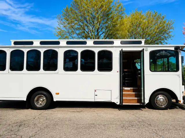 A white trolley parked beside a lawn under a blue sky.